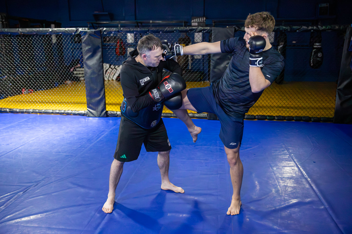 Two individuals practicing martial arts on a blue mat.