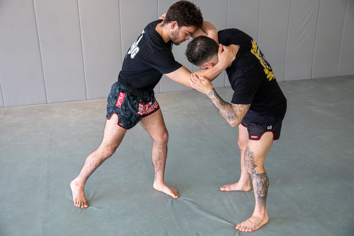 Two fighters training on clinch and knees in a martial arts gym