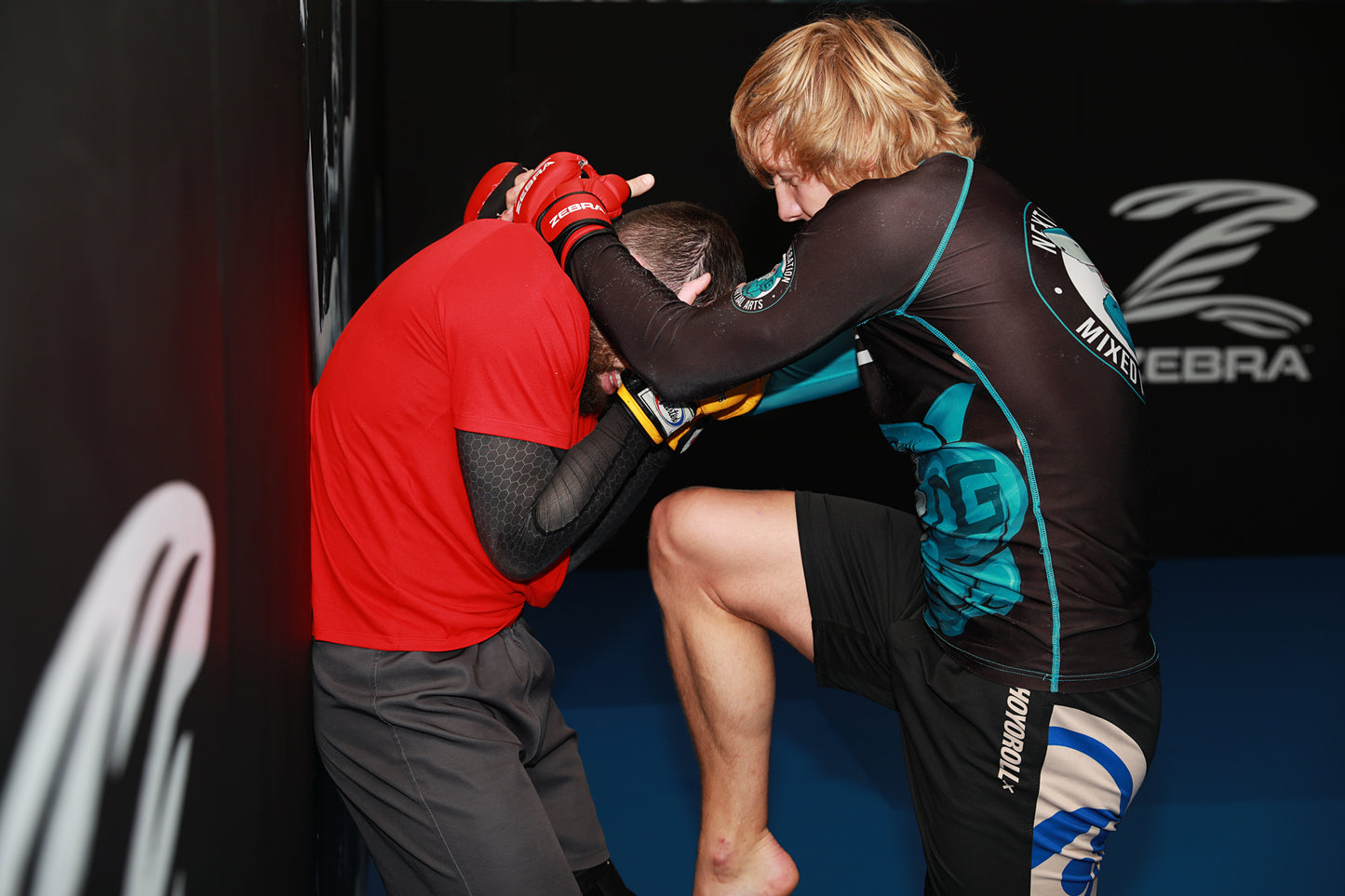 A photo of Paddy and Adam demonstrating striking against the cage wall in training