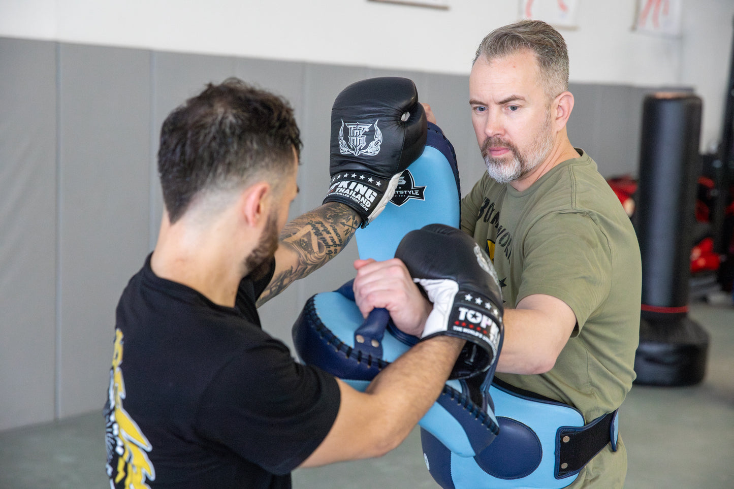 A photo of a coach holding pads for an athlete