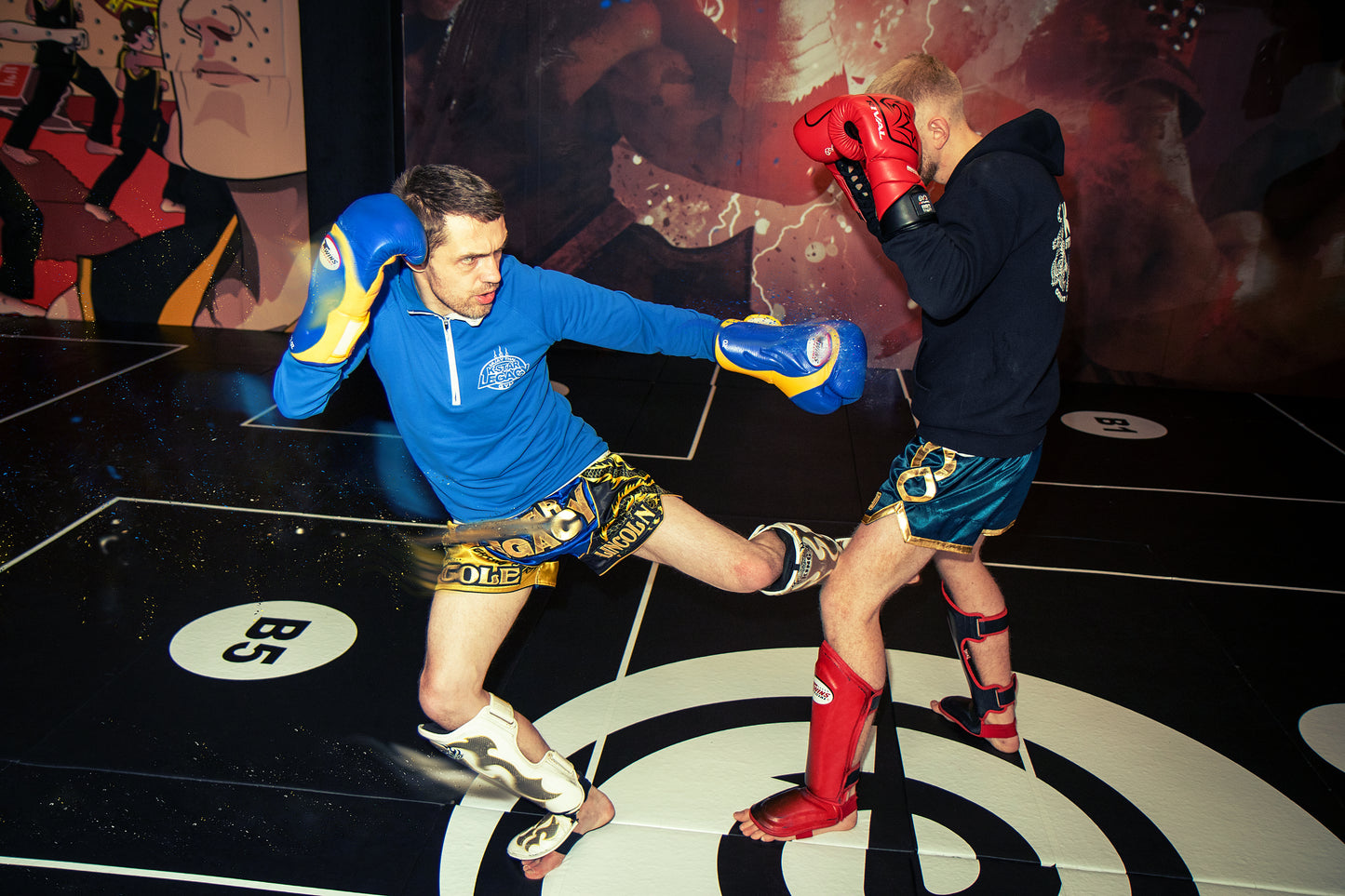 A photo of a Muay Thai fighter demonstrating a low kick on a training partner