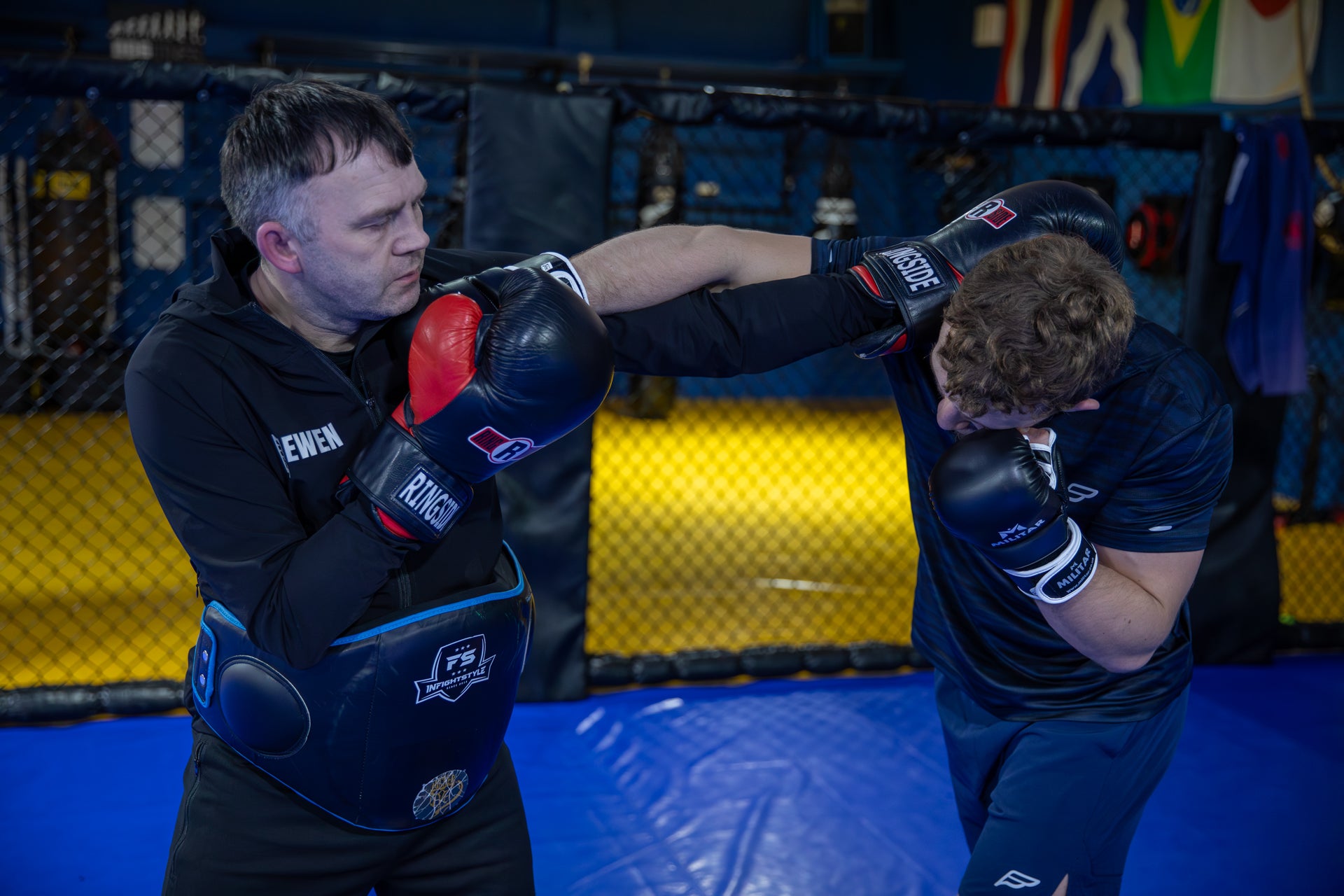 A photo of a coach holding pads for a fighter