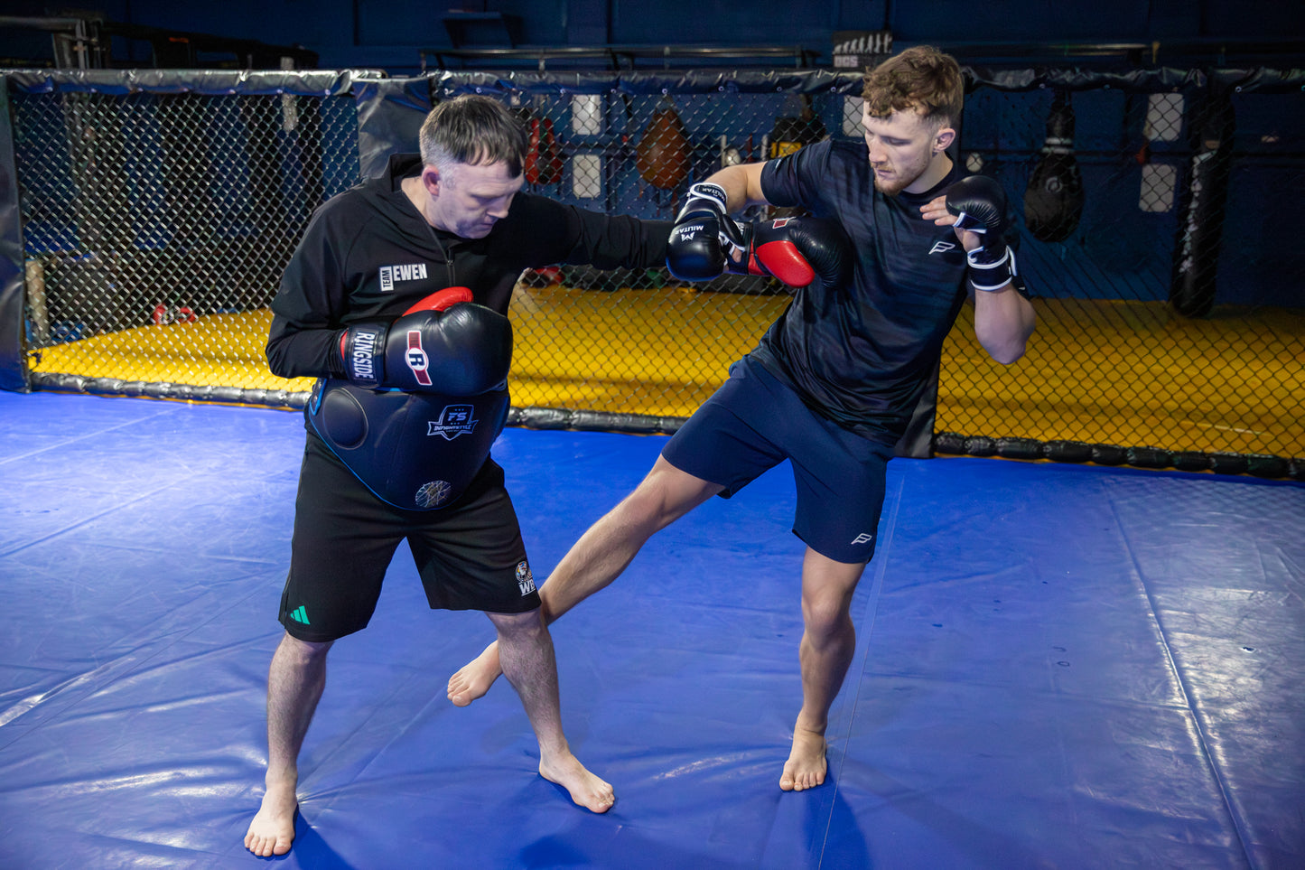 A photo of a coach holding pads for a fighter
