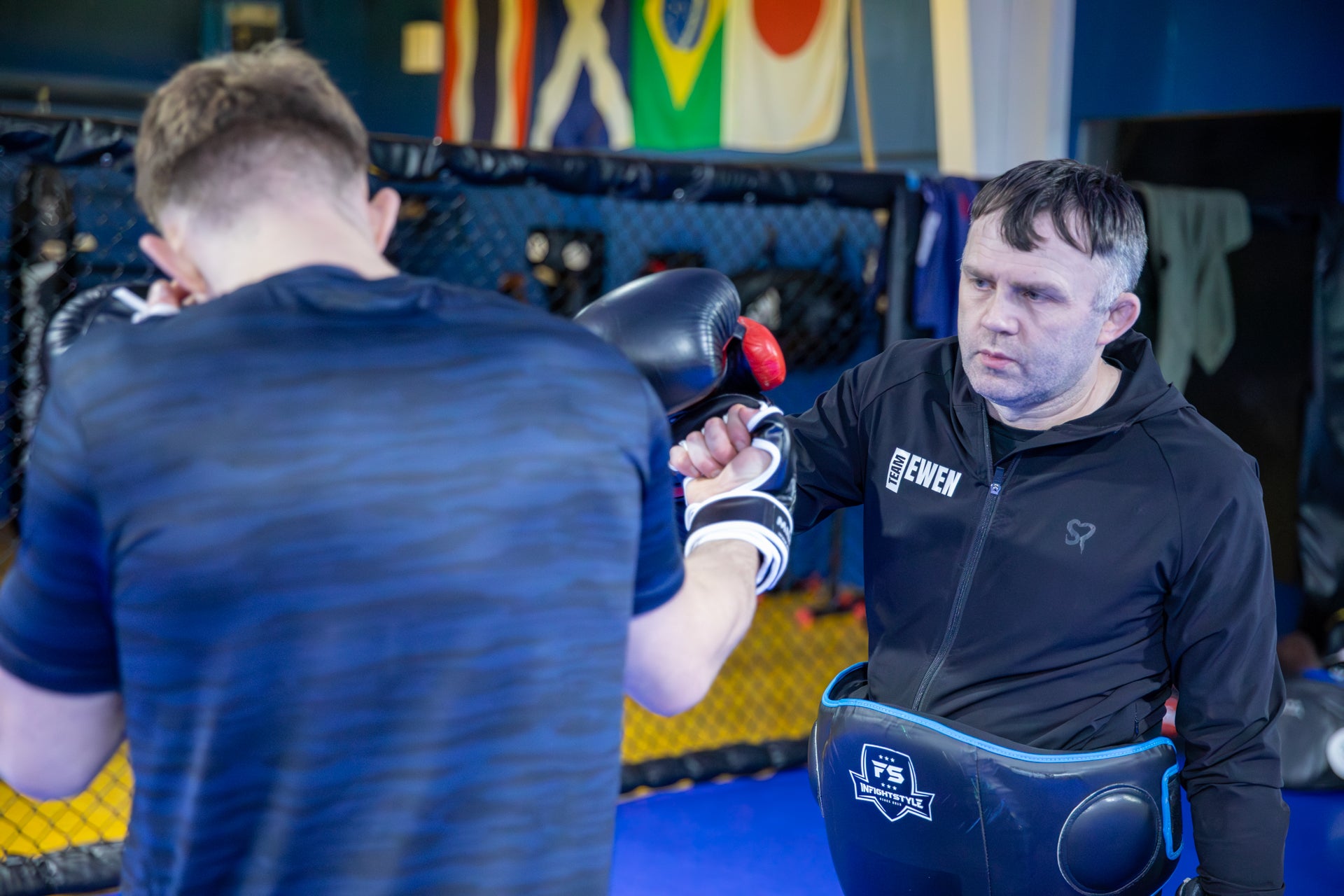 A photo of a coach holding pads for a fighter