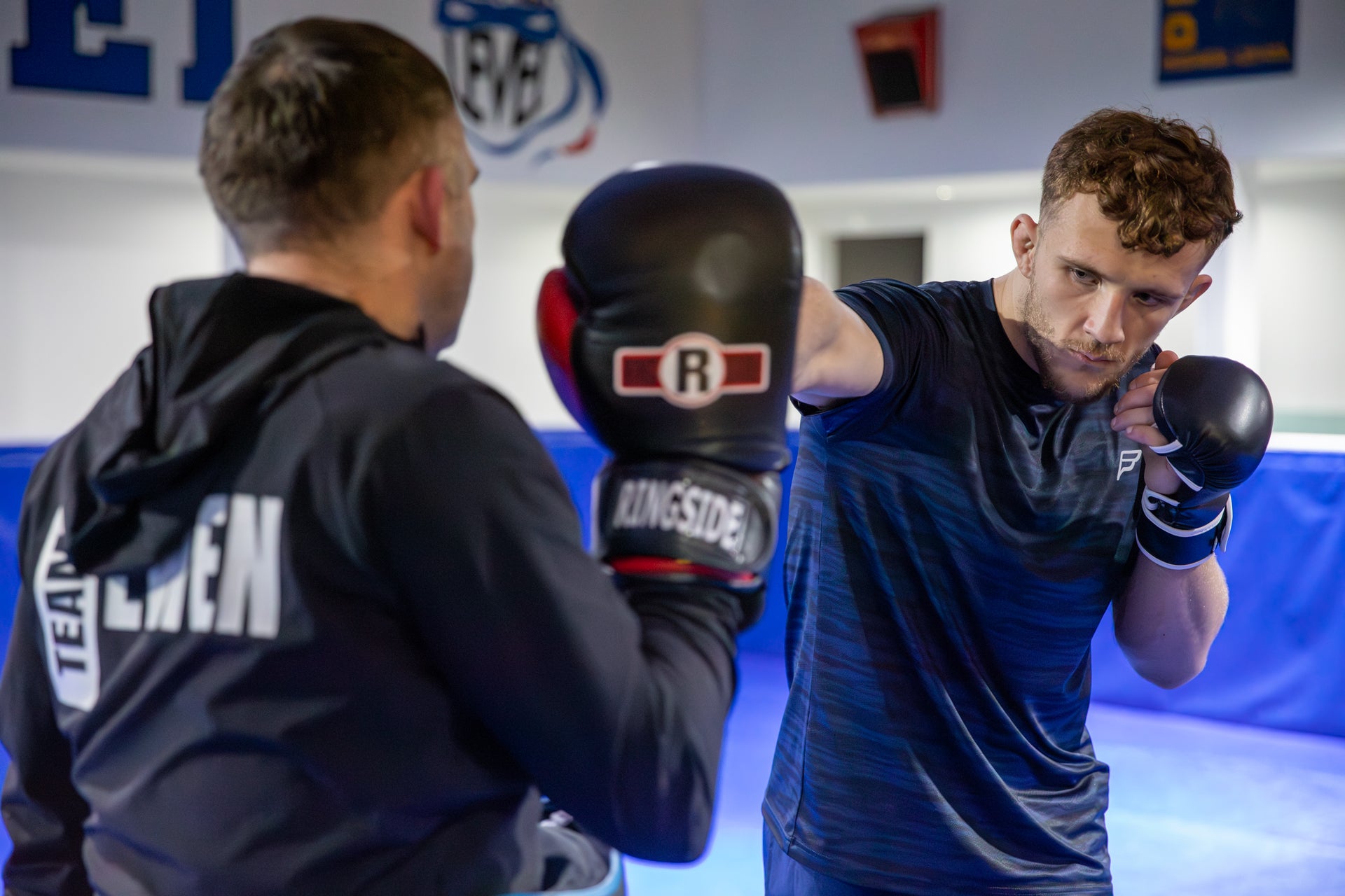 A photo of a coach holding pads for a fighter