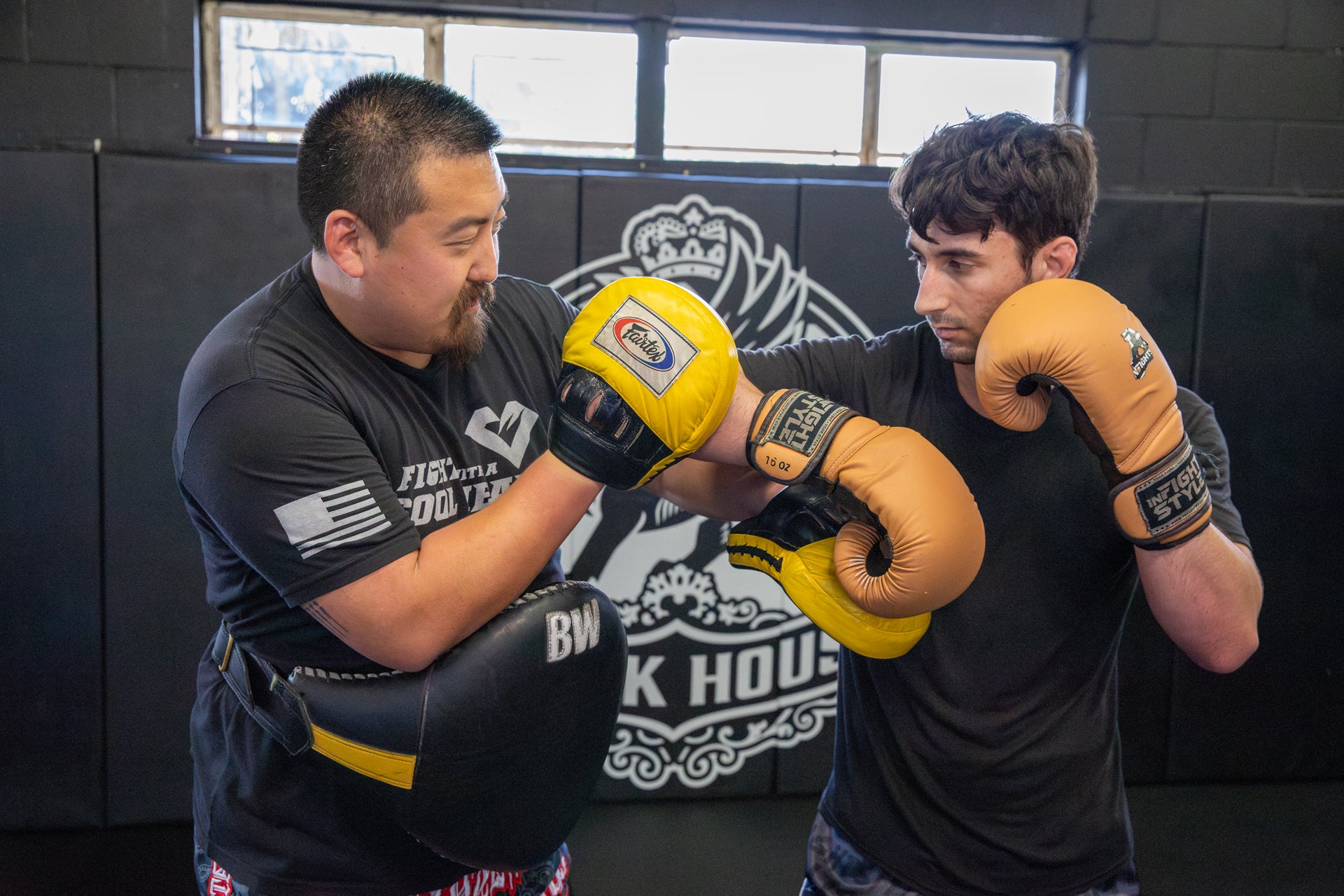 This is a photo of Jason Park holding pads in Muay Thai