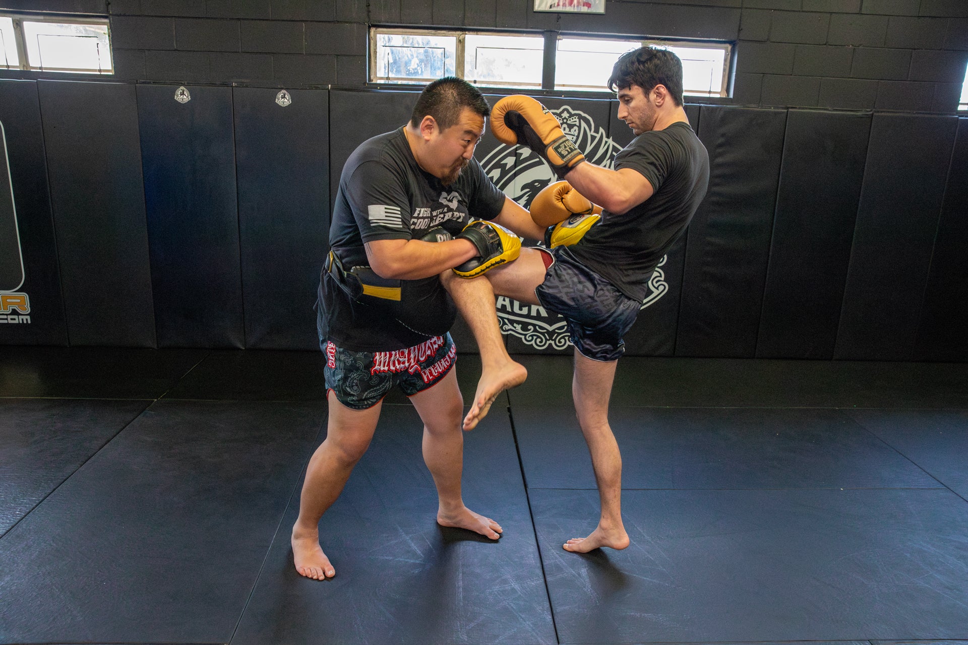 This is a photo of Jason Park holding pads in Muay Thai