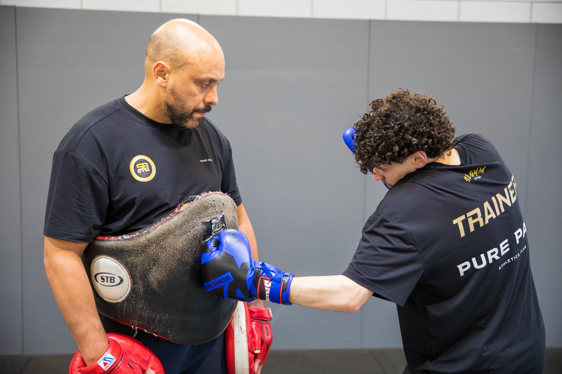 A fighter working a body shot onto his coaches belly pad