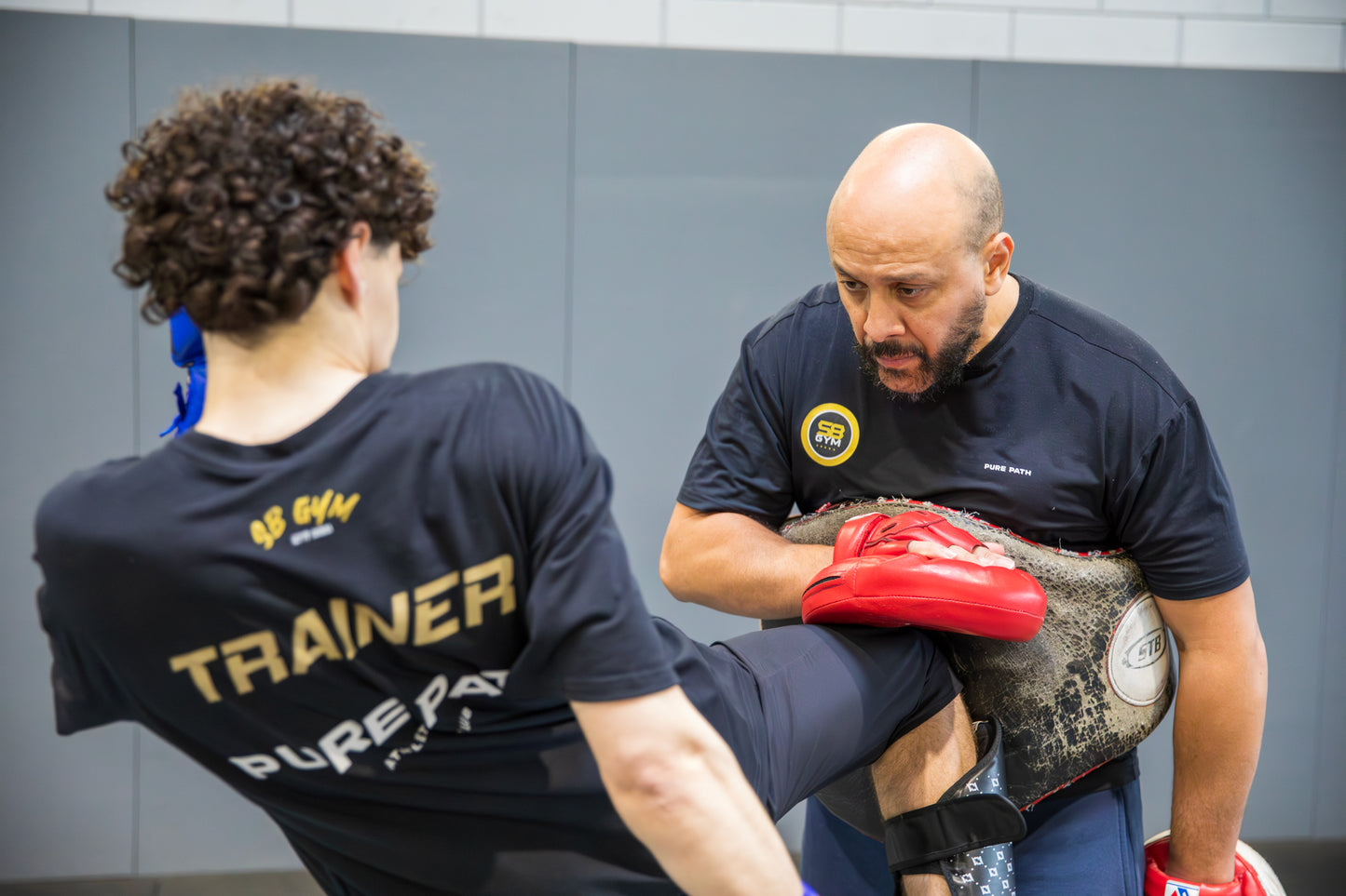 A fighter executing a knee strike onto his coaches belly pad