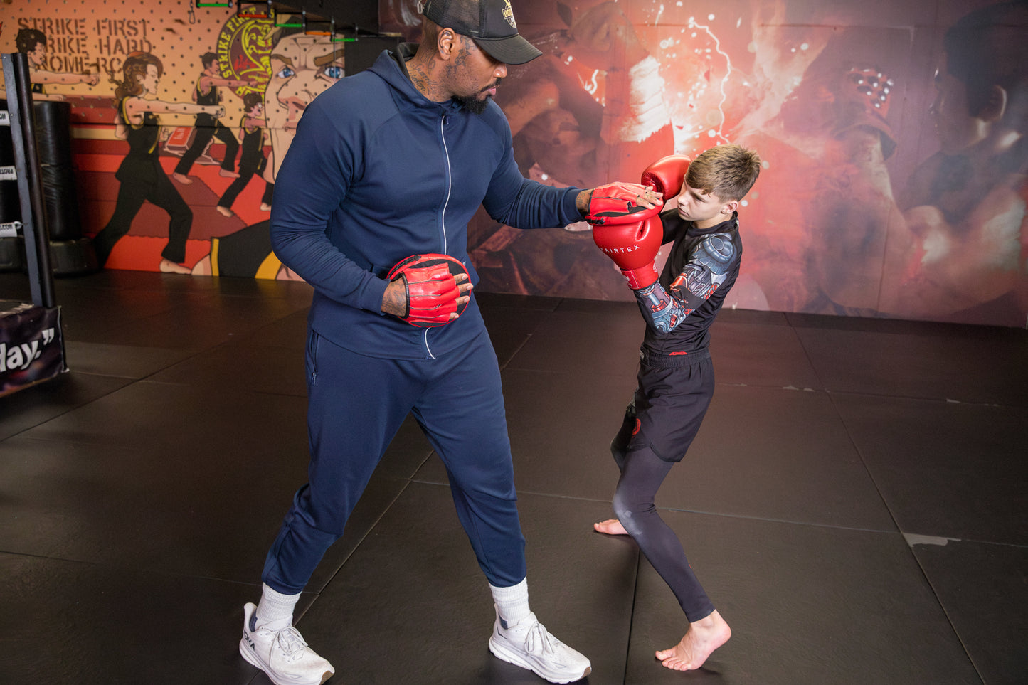 A photo of a boxing coach demonstrating pad work