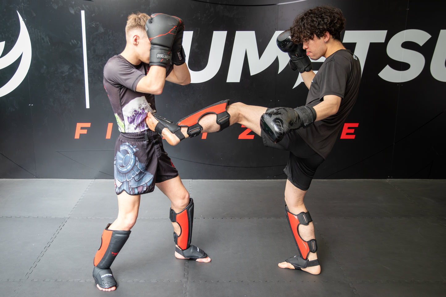 Two individuals practicing martial arts in a gym setting with ‘Fumetsu' branding.