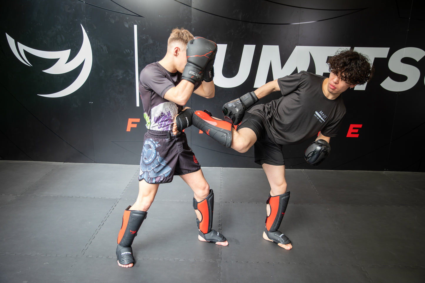 Two individuals practicing martial arts in a gym setting with ‘Fumetsu' branding.