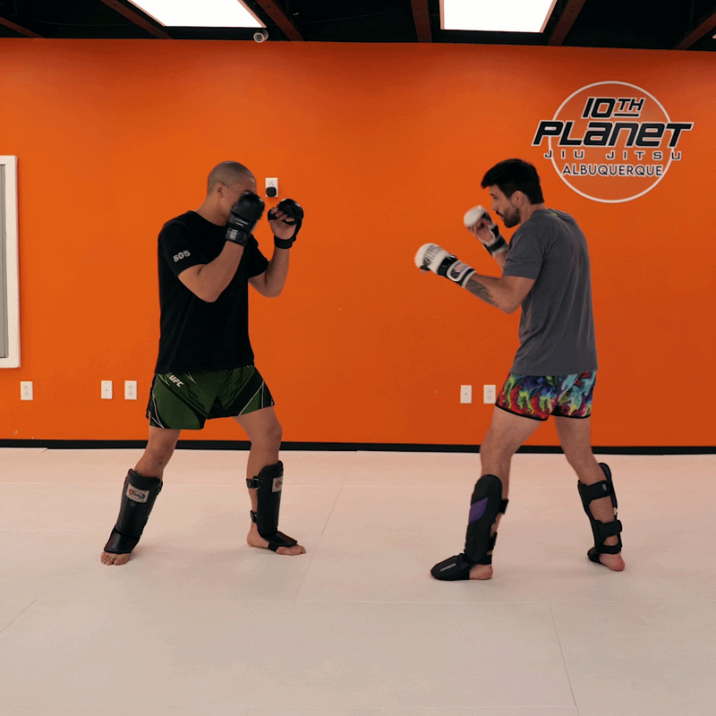 Two fighters training together in a martial arts gym