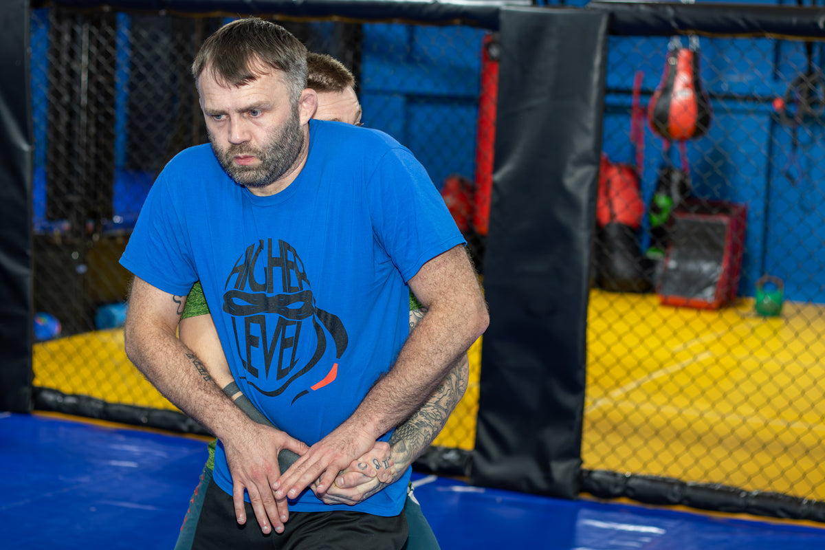 A coach training with his fighter in a martial arts gym