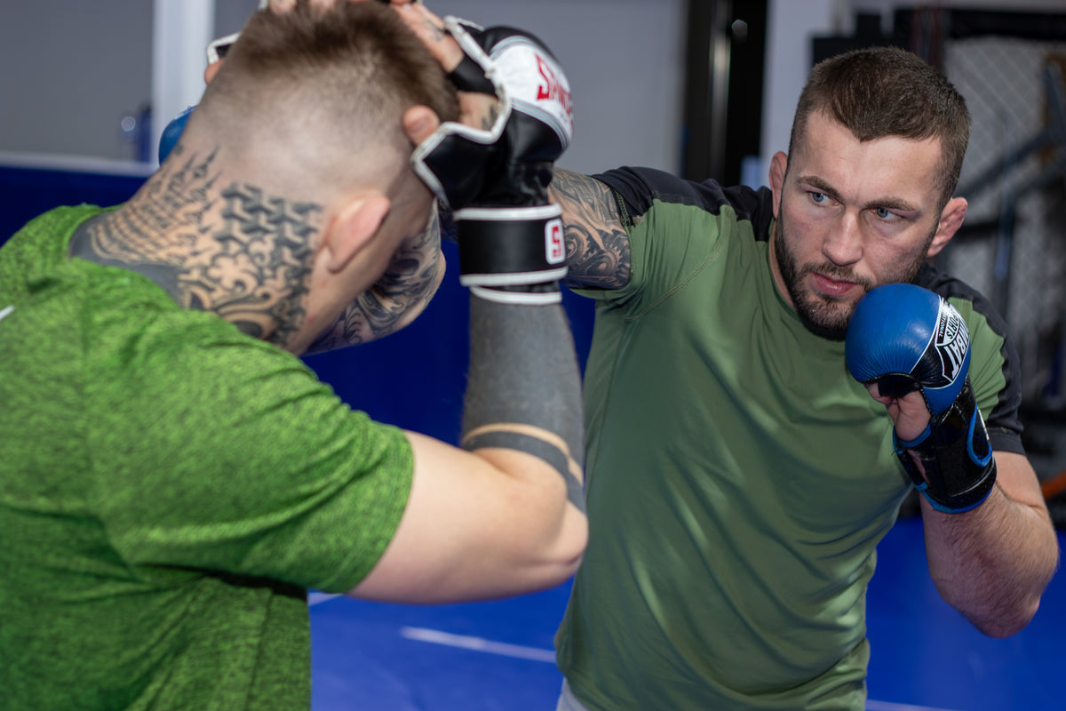 a fighter throwing a punch towards his training partner in a martial arts gym
